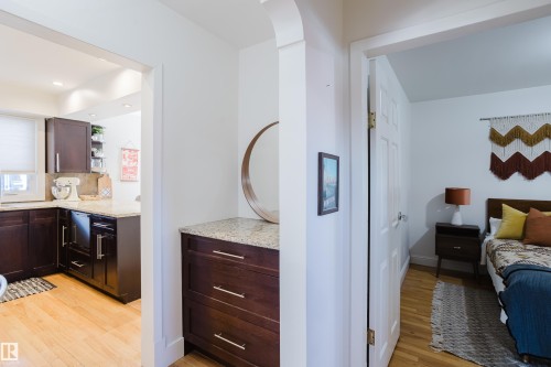 The property features a kitchen with dark wood cabinetry, light-colored granite countertops, and light wood flooring - 10643 66 Avenue, Edmonton, AB - Indoor Photo Showing Bedroom