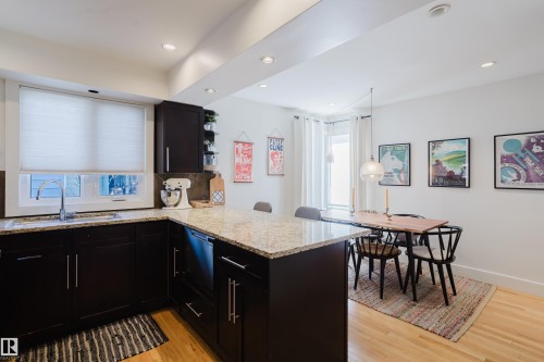 The kitchen features dark wood cabinetry, light granite countertops, and a window above the sink - 10643 66 Avenue, Edmonton, AB - Indoor