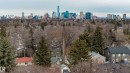 Elevated view of the surrounding residential area featuring a mix of mature evergreen and deciduous trees, with a distant city skyline visible - 10643 66 Avenue, Edmonton, AB  - Outdoor With View 