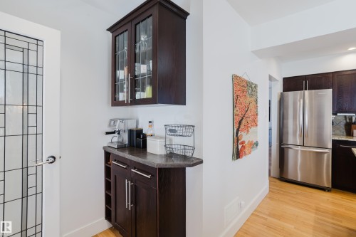 The property features a built-in dark wood cabinet with glass-fronted doors, offering additional storage - 10643 66 Avenue, Edmonton, AB - Indoor Photo Showing Kitchen