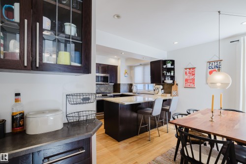 The kitchen features rich dark cabinetry, granite countertops, and light hardwood flooring - 10643 66 Avenue, Edmonton, AB - Indoor