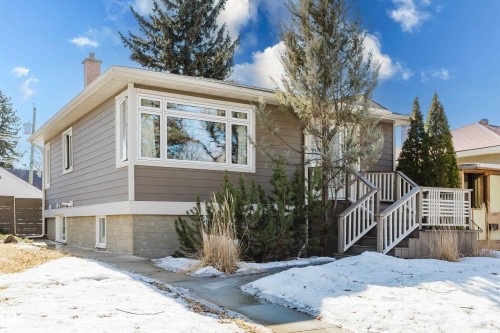 The property features a charming exterior with neutral-toned siding, a bay window, and a welcoming front porch with white railings - 10643 66 Avenue, Edmonton, AB - Outdoor