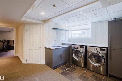 The property features a laundry area with a utility sink, a countertop, and built-in cabinetry, complemented by a window providing natural light - 10643 66 Avenue, Edmonton, AB - Indoor Photo Showing Laundry Room