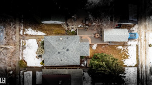 Aerial view of the property showing a main residence with a gray shingle roof, a detached garage, and a spacious yard with a mix of green and bare ground - 10643 66 Avenue, Edmonton, AB - Outdoor