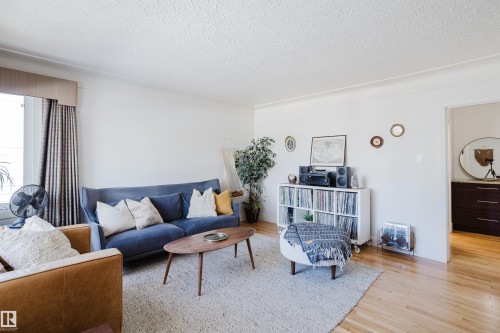 Living area featuring hardwood flooring, a window with curtains, and white walls - 10643 66 Avenue, Edmonton, AB - Indoor Photo Showing Living Room