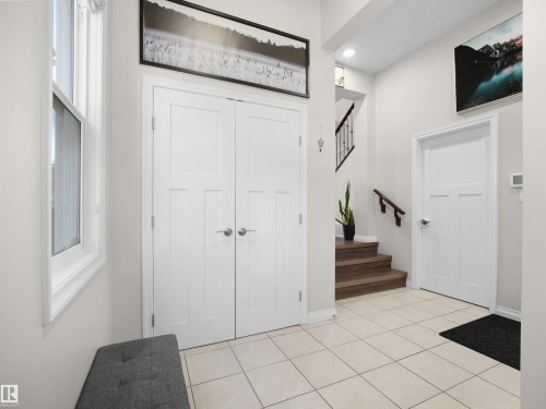 The property features a bright entryway with a large window, light-colored tile flooring, and a staircase with wooden treads and a handrail - 4405 Crabapple Landing Landing, Edmonton, AB - Indoor Photo Showing Other Room