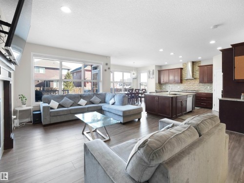 Open concept living space featuring hardwood floors, large windows providing natural light, a kitchen with a center island and wood cabinetry, and recessed lighting throughout - 4405 Crabapple Landing Landing, Edmonton, AB - Indoor Photo Showing Living Room