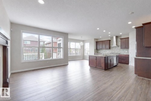 Open concept living area with light wood flooring, a kitchen island, and multiple windows - 4405 Crabapple Landing Landing, Edmonton, AB - Indoor Photo Showing Kitchen With Upgraded Kitchen