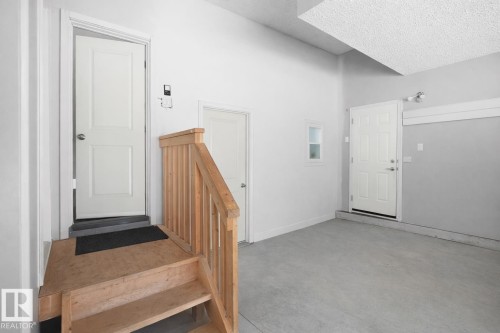 The property features a concrete floor, light-colored walls, and a wooden staircase with a wooden railing - 4405 Crabapple Landing Landing, Edmonton, AB - Indoor Photo Showing Other Room