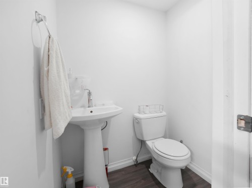 Powder room featuring a pedestal sink, a toilet, and dark wood flooring - 4405 Crabapple Landing Landing, Edmonton, AB - Indoor Photo Showing Bathroom