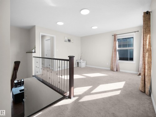 This bright loft space features neutral carpeting, a large window with drapes, and recessed lighting - 4405 Crabapple Landing Landing, Edmonton, AB - Indoor Photo Showing Other Room