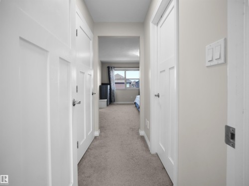 This property features a well-maintained hallway with light-colored carpeting, white paneled doors, and light-colored walls - 4405 Crabapple Landing Landing, Edmonton, AB - Indoor Photo Showing Other Room
