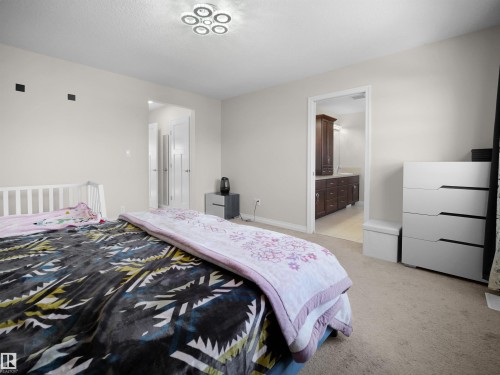 Bedroom with carpeted flooring, a contemporary ceiling light fixture, and an entryway to a room with a dark wood vanity - 4405 Crabapple Landing Landing, Edmonton, AB - Indoor Photo Showing Bedroom