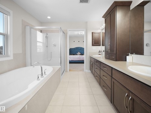 Well-appointed bathroom featuring a soaking tub with chrome fixtures, a glass-enclosed shower, and a vanity with dual sinks and ample storage - 4405 Crabapple Landing Landing, Edmonton, AB - Indoor Photo Showing Bathroom