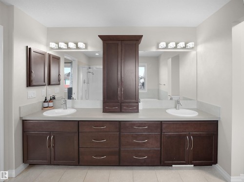 Bathroom featuring a spacious double vanity with dark wood cabinetry, light countertops, and integrated sinks - 4405 Crabapple Landing Landing, Edmonton, AB - Indoor Photo Showing Bathroom