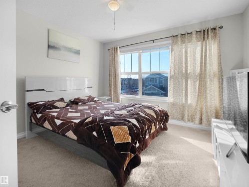 This room features large windows with curtains, carpeted flooring, and a ceiling fan with lighting - 4405 Crabapple Landing Landing, Edmonton, AB - Indoor Photo Showing Bedroom