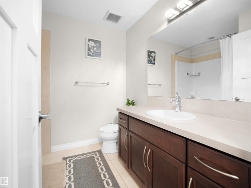 Well-appointed bathroom featuring a dark wood vanity with a light-colored countertop, a large mirror, and tiled flooring - 4405 Crabapple Landing Landing, Edmonton, AB - Indoor Photo Showing Bathroom