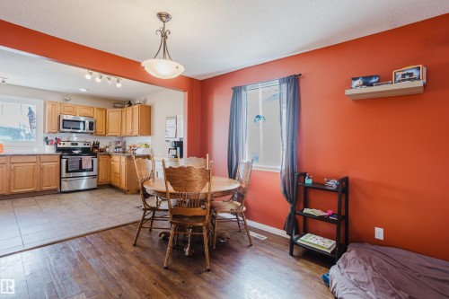 The dining area features wood flooring and a ceiling light fixture, with a window providing natural light - 8707 151 Avenue, Edmonton, AB - Indoor