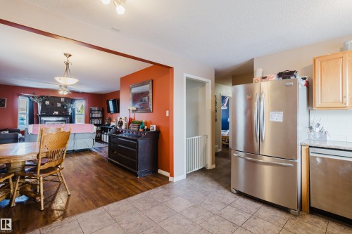Kitchen featuring stainless steel appliances including a refrigerator and dishwasher, with light wood cabinetry, a tiled backsplash, and granite countertops - 8707 151 Avenue, Edmonton, AB - Indoor