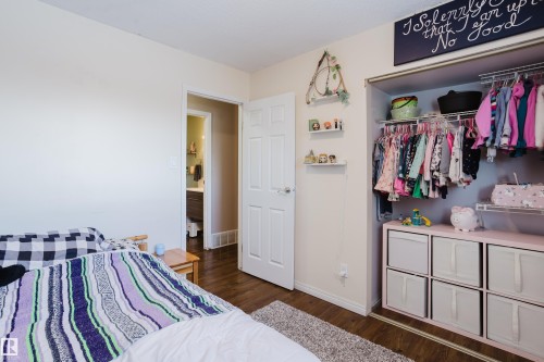 This room features rich wood flooring, a built-in closet with shelving and hanging rods, and a white paneled door - 8707 151 Avenue, Edmonton, AB - Indoor Photo Showing Bedroom