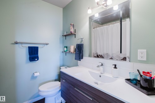 Bathroom featuring a vanity with a white countertop, a mirror with overhead lighting, and two wall-mounted shelves - 8707 151 Avenue, Edmonton, AB - Indoor Photo Showing Bathroom