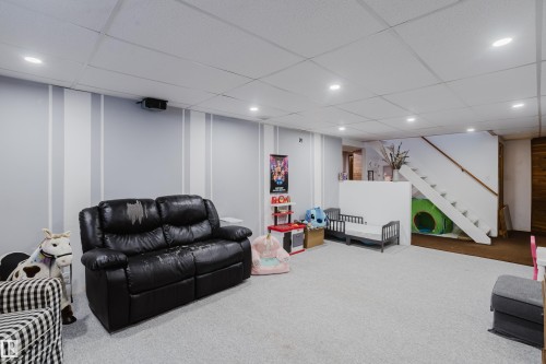 The spacious finished basement features recessed lighting, carpeted flooring, and a staircase with a wooden handrail - 8707 151 Avenue, Edmonton, AB - Indoor Photo Showing Basement