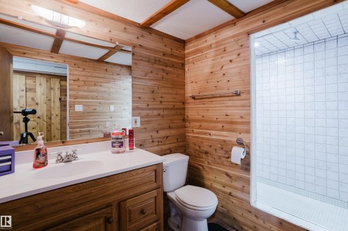 This bathroom features extensive wood paneling, a vanity with a built-in sink, and a tiled shower stall - 8707 151 Avenue, Edmonton, AB - Indoor Photo Showing Bathroom