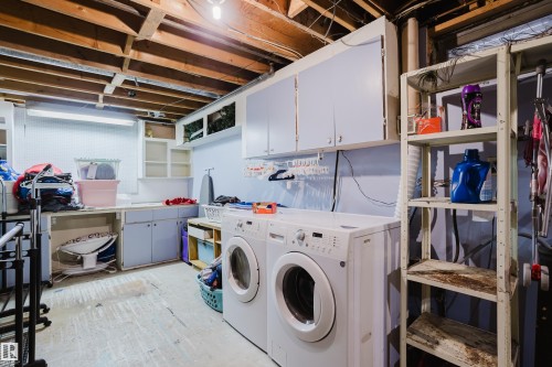 Dedicated laundry area with a washer and dryer, featuring overhead cabinetry for storage and an exposed beam ceiling - 8707 151 Avenue, Edmonton, AB - Indoor Photo Showing Laundry Room