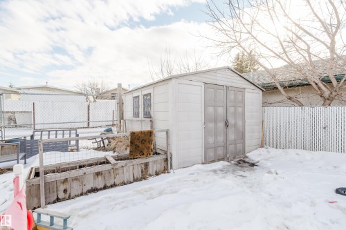 The property features a white outdoor storage shed with double doors and two windows - 8707 151 Avenue, Edmonton, AB - Outdoor