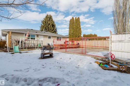The property features a spacious backyard with a deck, a paved patio area, and a large lawn - 8707 151 Avenue, Edmonton, AB - Outdoor
