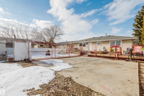The property features a spacious backyard with a concrete patio area, a raised wooden deck, and a fenced perimeter - 8707 151 Avenue, Edmonton, AB - Outdoor