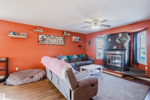 Living area featuring a fireplace with a dark surround, windows providing natural light, and a ceiling fan - 8707 151 Avenue, Edmonton, AB - Indoor Photo Showing Living Room With Fireplace