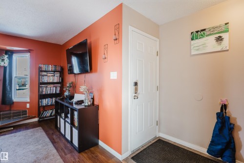 This property features hardwood flooring and a white front entry door with a smart lock - 8707 151 Avenue, Edmonton, AB - Indoor
