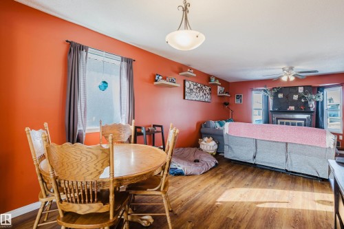 This room features warm-toned walls, wood-look flooring, and a ceiling light fixture - 8707 151 Avenue, Edmonton, AB - Indoor Photo Showing Dining Room