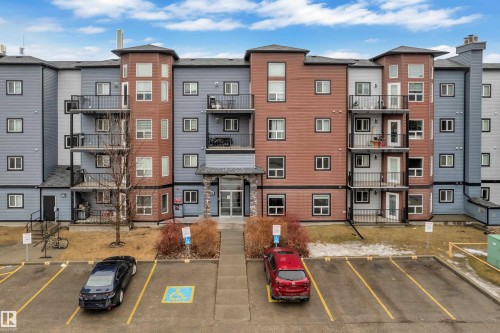 The property features a multi-story building with a facade combining grey siding and reddish-brown paneling, accented by black trim around the windows and balconies - 320 392 Silver Berry Road, Edmonton, AB - Outdoor With Facade