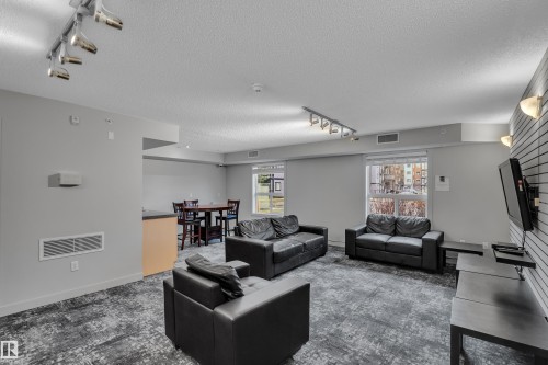 The living area features light grey walls, recessed and track lighting, and grey patterned carpeting - 320 392 Silver Berry Road, Edmonton, AB - Indoor Photo Showing Living Room