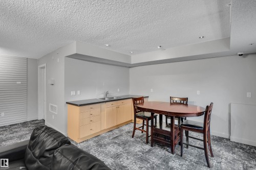 This versatile space features light-toned cabinetry with a sink and dark countertops, recessed lighting, and patterned carpeting - 320 392 Silver Berry Road, Edmonton, AB - Indoor Photo Showing Dining Room