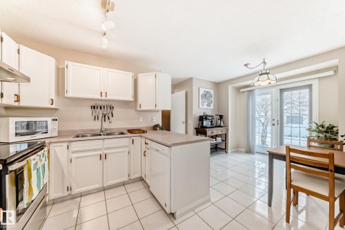 The kitchen features white cabinetry, a double basin sink, and a stainless steel oven - 11415 32 Avenue, Edmonton, AB - Indoor Photo Showing Kitchen With Double Sink