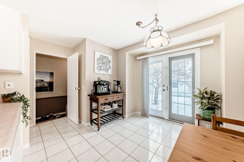 This area features white tile flooring, a charming hanging light fixture, and double glass doors providing outdoor access - 11415 32 Avenue, Edmonton, AB - Indoor