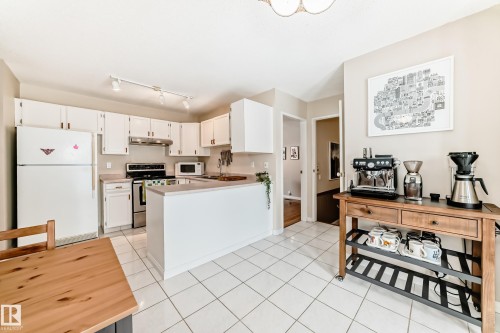 The kitchen features white cabinetry, white appliances, and a white tiled floor - 11415 32 Avenue, Edmonton, AB - Indoor Photo Showing Kitchen