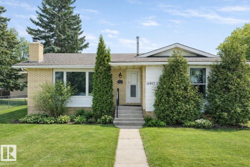 The property features a well-maintained front yard with a lush lawn, mature trees, and established landscaping - 11415 32 Avenue, Edmonton, AB - Outdoor