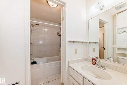 The bathroom features a vanity with an integrated sink, a large mirror, and overhead lighting - 11415 32 Avenue, Edmonton, AB - Indoor Photo Showing Bathroom