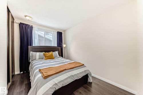 The room features dark wood flooring, a window with dark blue curtains, and a ceiling light fixture - 11415 32 Avenue, Edmonton, AB - Indoor Photo Showing Bedroom