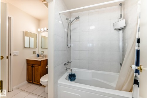 The bathroom features a tiled shower and bath combination, a vanity with a wooden cabinet, and a mirrored medicine cabinet with overhead lighting - 11415 32 Avenue, Edmonton, AB - Indoor Photo Showing Bathroom