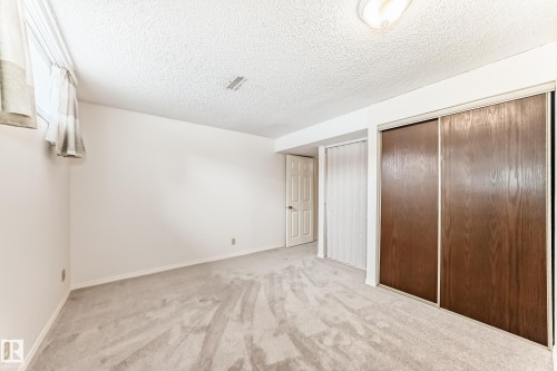 This room features light-colored carpeting, a window with curtains, and two sets of closets with sliding doors - 11415 32 Avenue, Edmonton, AB - Indoor Photo Showing Other Room