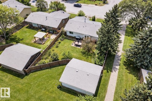 The property features an expansive green lawn, a wooden fence, and mature trees - 11415 32 Avenue, Edmonton, AB - Outdoor With View