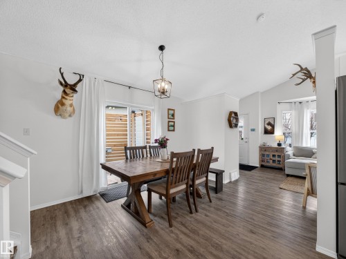 The dining area features wood-look flooring and a contemporary light fixture - 1665 Tompkins Place, Edmonton, AB - Indoor Photo Showing Dining Room