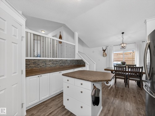 Kitchen and dining area featuring white cabinetry, a kitchen island, and a dining table with chairs - 1665 Tompkins Place, Edmonton, AB - Indoor Photo Showing Kitchen