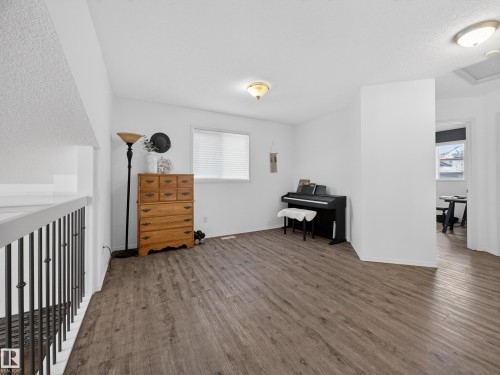 This versatile space features durable LVP flooring, a large window with blinds, and a neutral white color palette - 1665 Tompkins Place, Edmonton, AB - Indoor