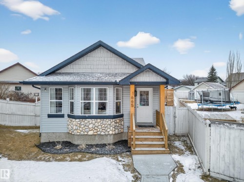 The property features light blue siding, a welcoming front entrance with wooden steps and a white door, and a bay window with a stone foundation - 1665 Tompkins Place, Edmonton, AB - Outdoor